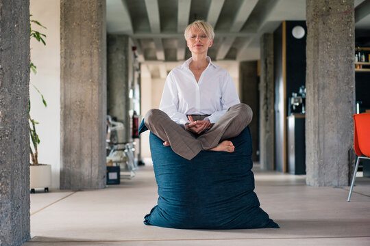 Businesswoman meditating on beanbag at home