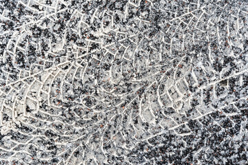 Multiple traces of car tires in the snow on the asphalt. Close up view from above