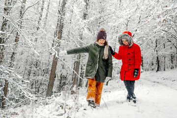 Teenage girl with sister walking on snow in forest during winter