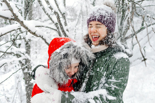 Cheerful teenage girl embracing sister while snowing during vacations