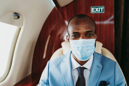 Young male entrepreneur with protective face mask in airplane