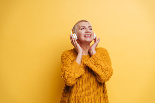 Happy Woman Wearing Headphones Looking Away While Standing Against Yellow Background