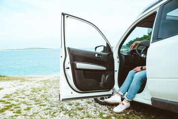 men legs stick out from car parked at sea beach