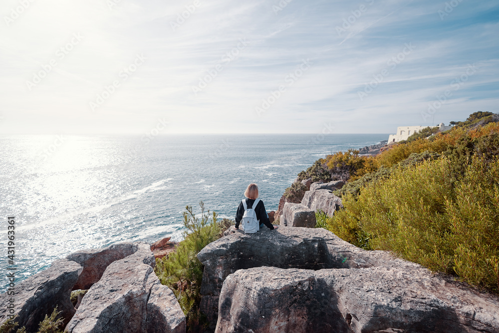 Wall mural Tourism concept. Young traveling woman with rucksack enjoying ocean view.