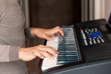 Fototapeta na wymiar Close-up of male hands playing keyboard piano at home