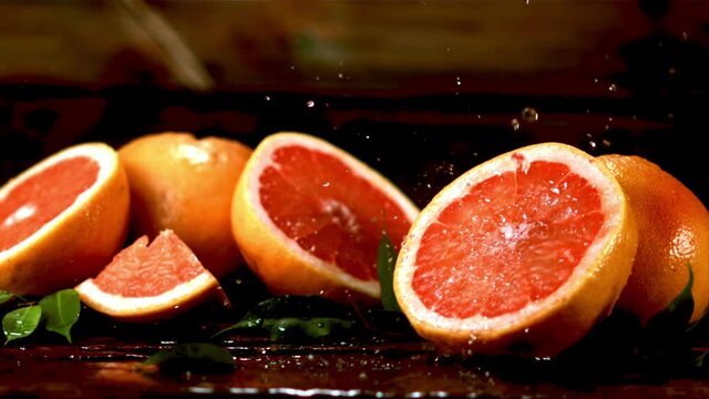 Super slow motion on fresh pieces of grapefruit drop drops of water. Filmed at 1000 fps.On a wooden background. 