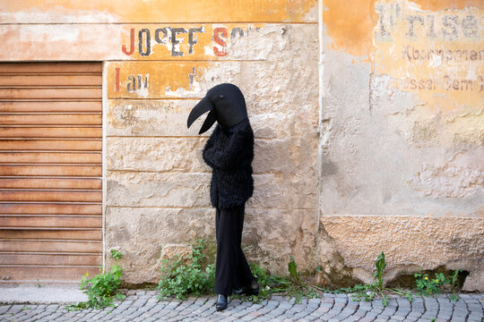 Woman with crow costume standing against old wall