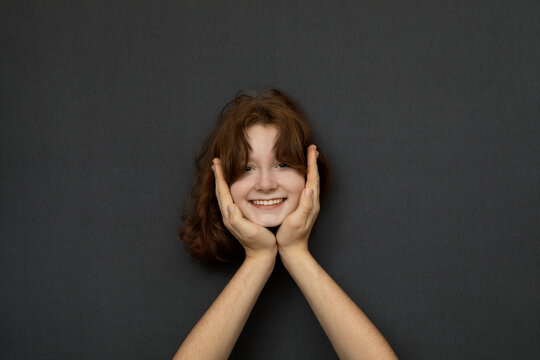 Studio shot of head of teenage girl leaning on male hands