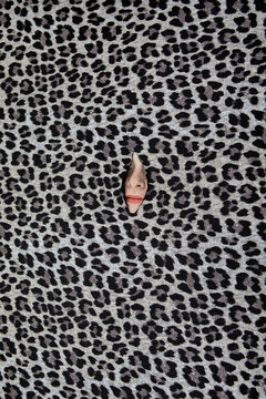 Nose of teenage girl peeking through hole in leopard print pattern