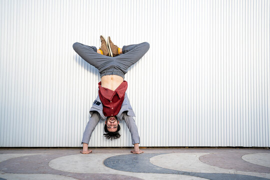 Male business professional doing handstand in front of wall