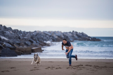 middle-aged boy playing with his dog on the beach