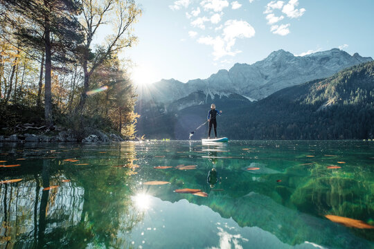 Germany, Bavaria, Garmisch Partenkirchen, Young woman stand up paddling on Lake Eibsee