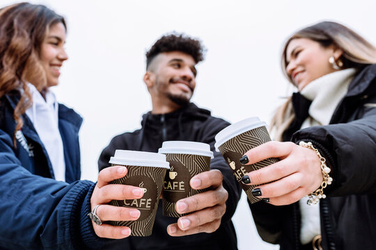 Smiling friend toasting coffee cups while looking at each other