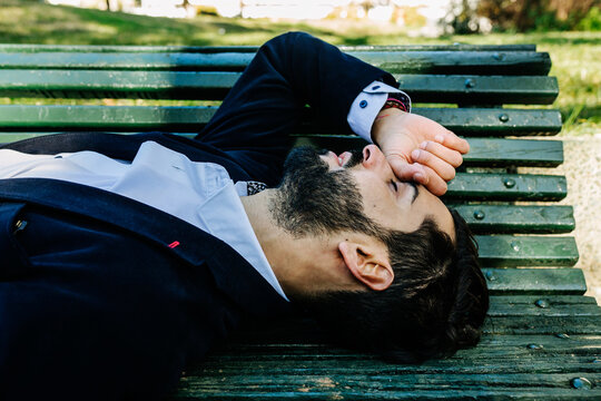 Businessman with eyes closed lying on bench at park