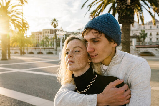 Affectionate young couple with arm around looking away