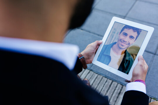 Businessman talking with friend over digital tablet while standing outdoors
