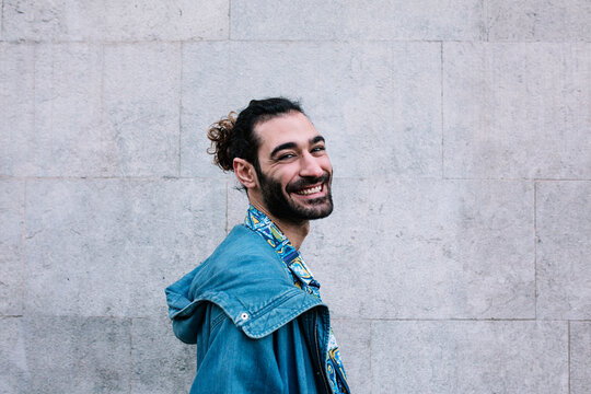 Smiling Young Man With Denim Jacket Standing In Front Of Wall