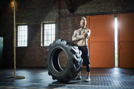 Confident male fitness instructor with arms crossed in gym