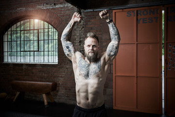 Active male athlete clenching fist while exercising in gym