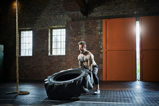 Determinant sportsman lifting tire while exercising at gym