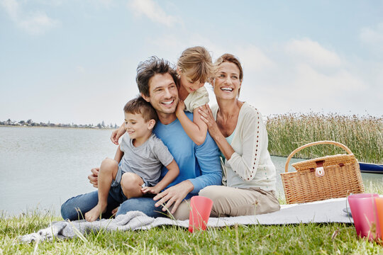 Happy family sitting in a line on blanket by lake