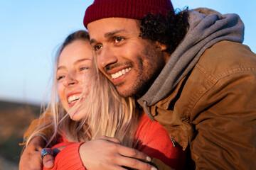 Man looking away while embracing woman outdoors