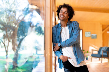 Smiling man looking through window while standing at front yard