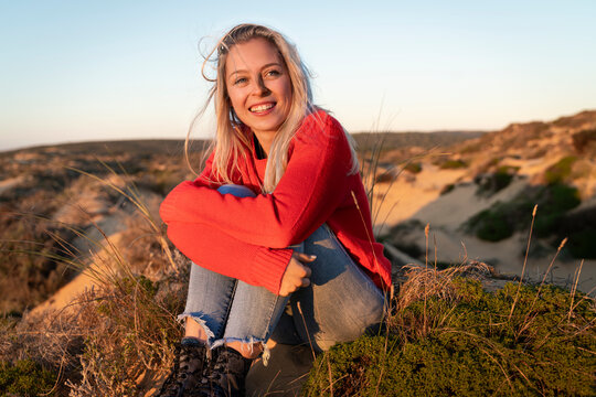 Young woman hugging knees while sitting on sand dune