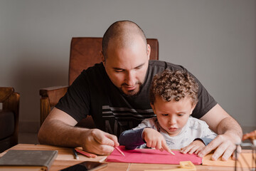Fototapeta na wymiar Father and son drawing pictures on a colored pad