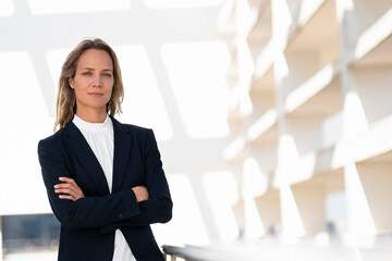 Confident female professional standing with arms crossed at office building terrace