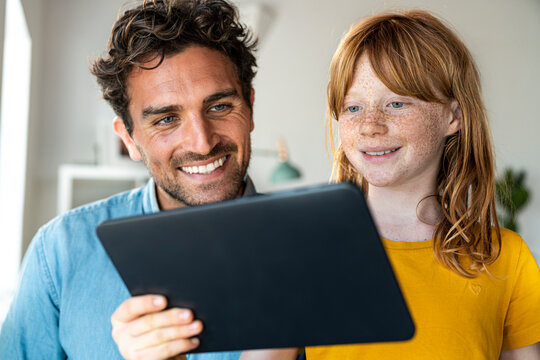 Redhead girl with father looking at laptop at home