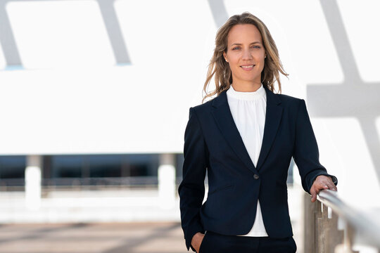 Smiling businesswoman with hands in pockets standing at building terrace