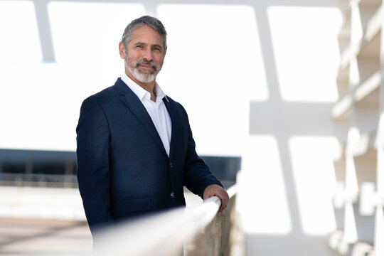 Smiling entrepreneur standing by railing at office terrace