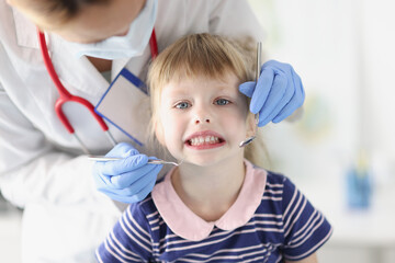 Little girl doctor dentist conducts an examination of oral cavity