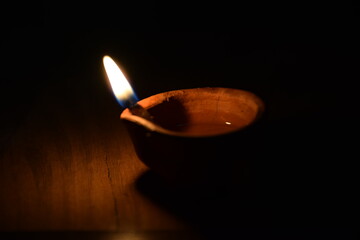 Close up image of a lit clay diya or lamp on floor on Diwali - an Indian hindu festival of lights isolated on black background., Selective focus