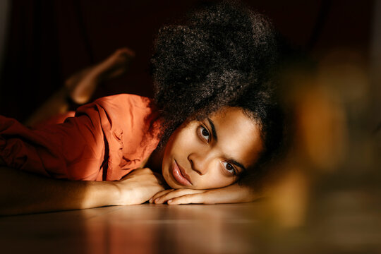 Afro young woman lying on floor at home