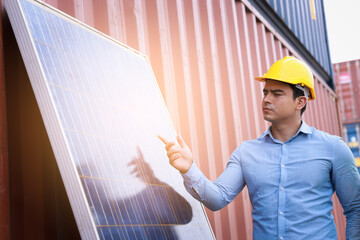 american engineer man wearing helmet safety and pointing hand to solar cell and container background engineering energy concept