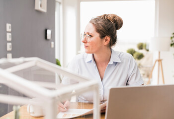 Businesswoman wearing eyeglasses sitting at desk looking away