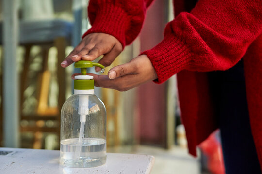 Woman using hand sanitizer while standing outdoors during COVID-19