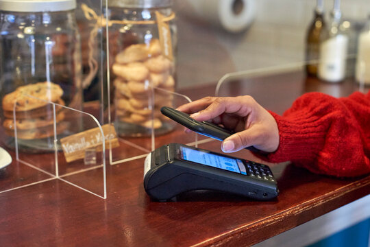 Woman paying through mobile phone at coffee shop