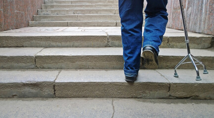 Elderly man with support cane stepping up stairs