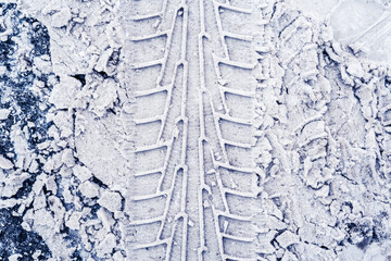 Vertical traces of car tires in the snow on the asphalt. Close up view from above