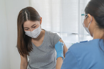 Covid-19, coronavirus asian young woman getting vaccine from doctor or nurse giving syringe shot to...