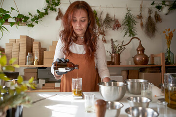 Mature woman pouring essential oil in beaker at workshop