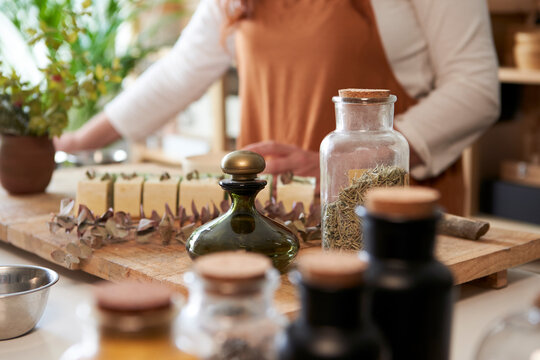 Woman decorating organic soap with rosemary leaves at workshop