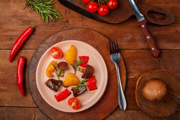 Antipasta on a plate on a stand on a wooden table next to fresh bright vegetables.