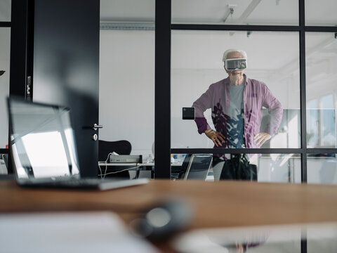 Senior businessman using virtual reality headset while standing in office