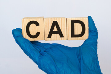 A doctor wearing gloves holds wooden cubes with the inscription CAD, medical concept