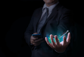Fototapeta premium Business man holding holographic graphs and stock market statistics gain profits, Display of good economy form digital screen,Concept of growth planning and business strategy.