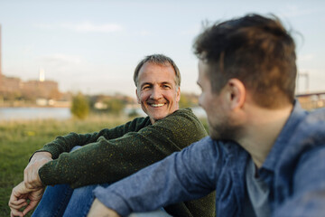 Smiling father spending leisure time with son at riverbank